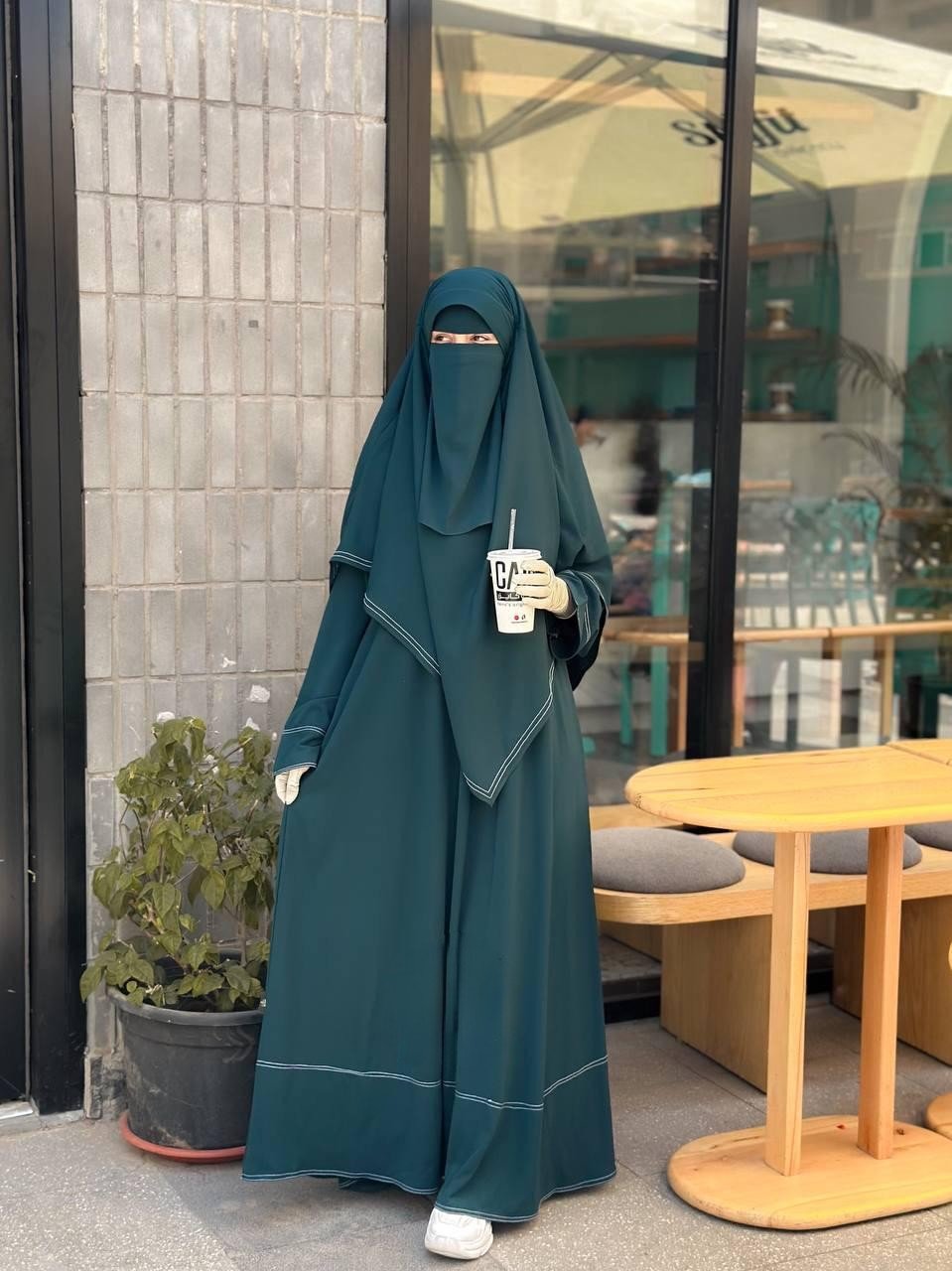 Front full-length view of a woman wearing the Dark Green Souda set holding a coffee cup.